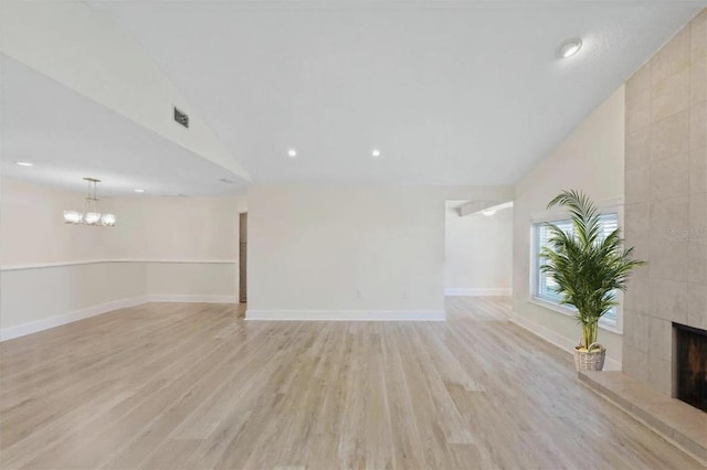 5033 Cabrilla Ct, New Port Richey, FL 34652 - unfurnished living room with vaulted ceiling, light wood-style floors, a tile fireplace, a chandelier, and recessed lighting