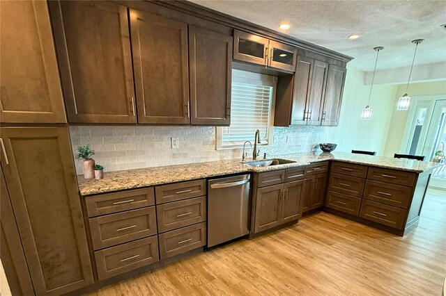 5033 Cabrilla Ct, New Port Richey, FL 34652 - kitchen featuring dishwasher, a peninsula, light wood-type flooring, backsplash, and a textured ceiling