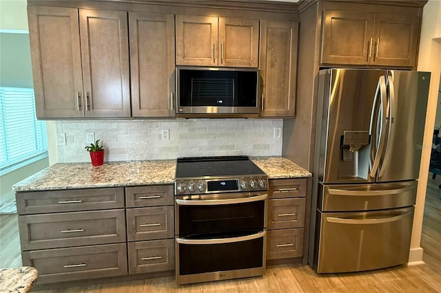 5033 Cabrilla Ct, New Port Richey, FL 34652 - kitchen featuring stainless steel appliances, light wood-style floors, backsplash, and light stone countertops