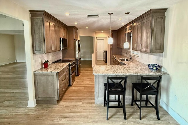 5033 Cabrilla Ct, New Port Richey, FL 34652 - kitchen with appliances with stainless steel finishes, light stone countertops, tasteful backsplash, a peninsula, and a kitchen breakfast bar