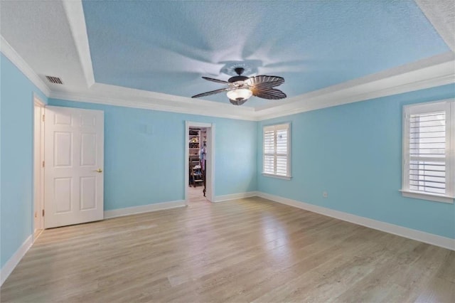 5033 Cabrilla Ct, New Port Richey, FL 34652 - spare room featuring a tray ceiling, a textured ceiling, healthy amount of natural light, ceiling fan, and light wood-style flooring