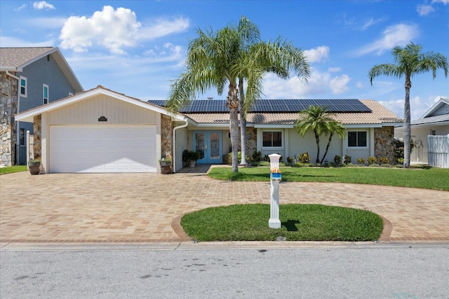 5033 Cabrilla Ct, New Port Richey, FL 34652 - single story home with stone siding, french doors, decorative driveway, an attached garage, and solar panels