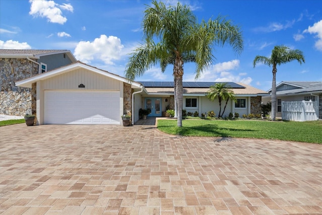 5033 Cabrilla Ct, New Port Richey, FL 34652 - view of front of property featuring stone siding, french doors, a front yard, decorative driveway, and an attached garage