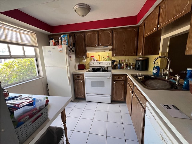 kitchen with under cabinet range hood, light countertops, a sink, light tile patterned flooring, and white appliances
