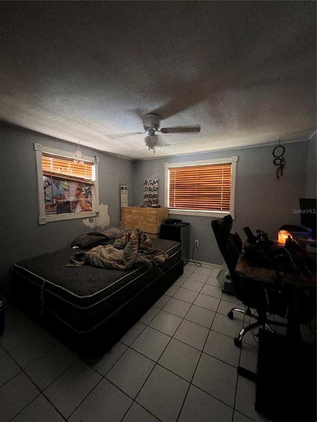 bedroom featuring a ceiling fan, a textured ceiling, and light tile patterned floors