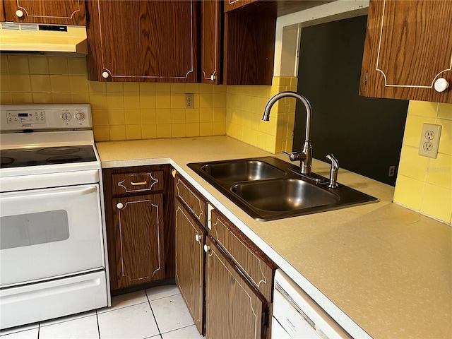 kitchen featuring under cabinet range hood, light countertops, a sink, white electric range oven, and tasteful backsplash