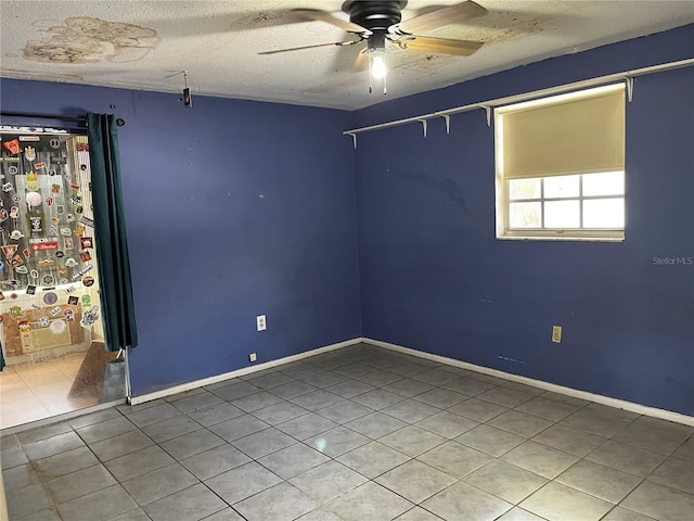 spare room featuring tile patterned floors, baseboards, a textured ceiling, and ceiling fan