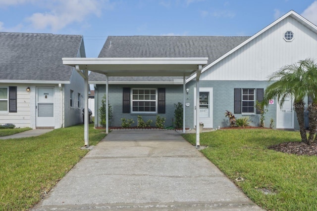 view of front of house with roof with shingles, a front lawn, and brick siding