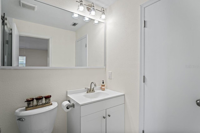 bathroom with toilet, visible vents, and vanity