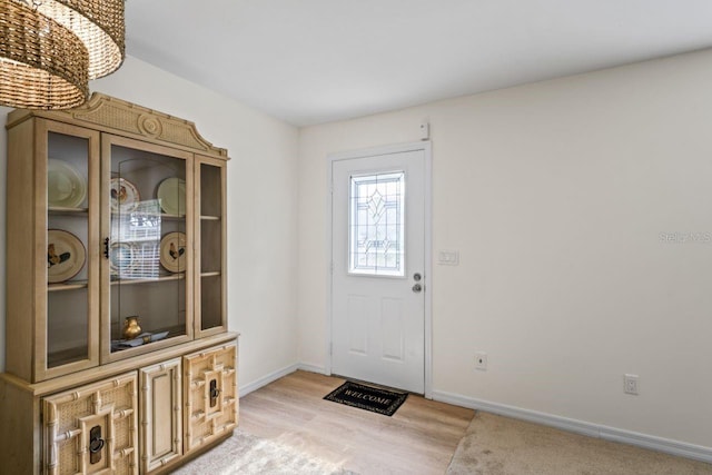 foyer featuring baseboards, a chandelier, and light wood-style floors