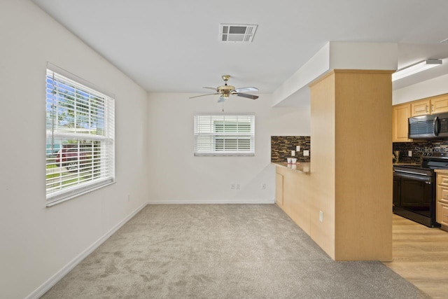 interior space featuring baseboards, a ceiling fan, light colored carpet, and visible vents