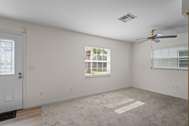 carpeted empty room with visible vents, baseboards, and ceiling fan