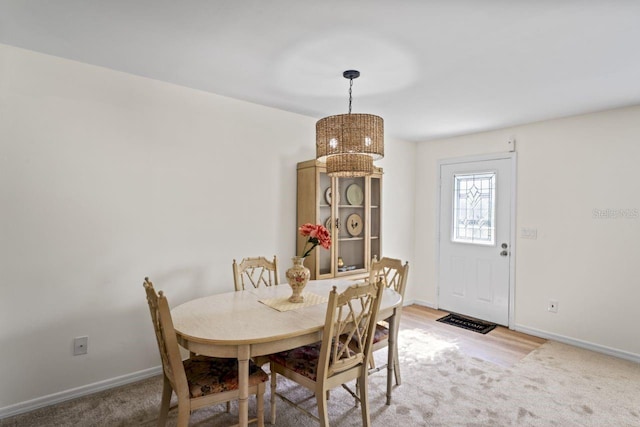 dining area with baseboards, a chandelier, and light carpet