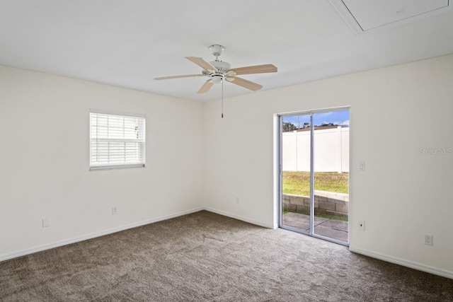 carpeted spare room with ceiling fan, baseboards, and attic access