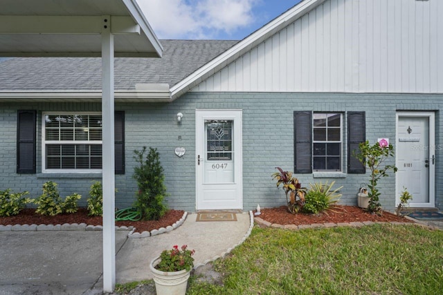 entrance to property with board and batten siding, brick siding, and roof with shingles