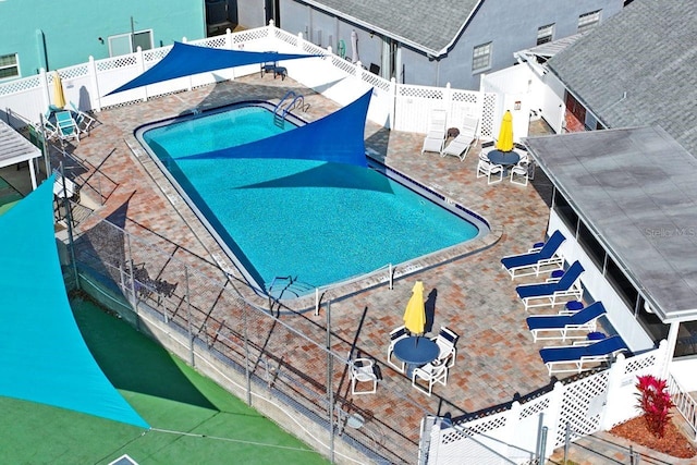 community pool with a fenced backyard and a patio area