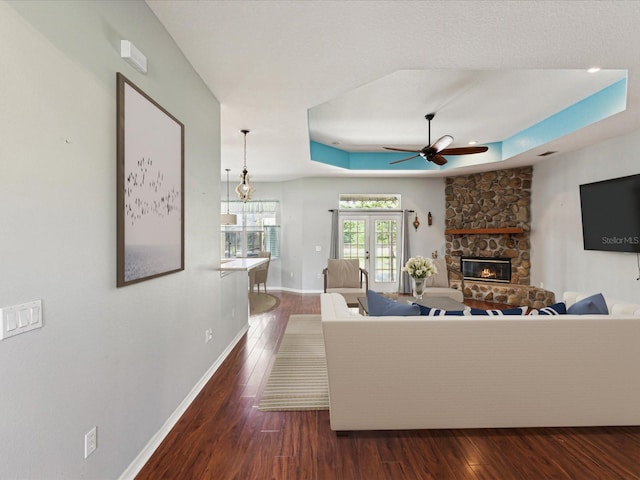 10318 Piper Dr, New Port Richey, FL 34654 - living room with a raised ceiling, baseboards, dark wood-style flooring, a ceiling fan, and a stone fireplace