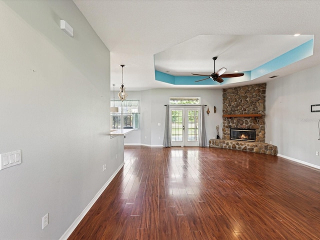 10318 Piper Dr, New Port Richey, FL 34654 - unfurnished living room featuring ceiling fan, a raised ceiling, a stone fireplace, baseboards, and wood finished floors