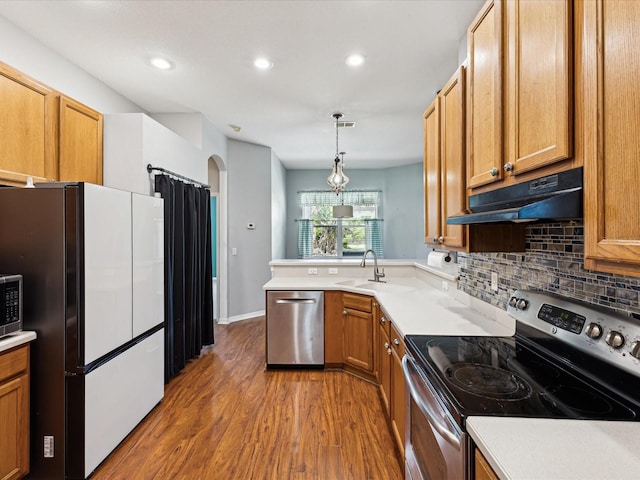 10318 Piper Dr, New Port Richey, FL 34654 - kitchen with decorative backsplash, stainless steel appliances, under cabinet range hood, wood finished floors, and a peninsula