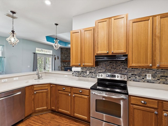 10318 Piper Dr, New Port Richey, FL 34654 - kitchen featuring a sink, under cabinet range hood, light countertops, pendant lighting, and appliances with stainless steel finishes