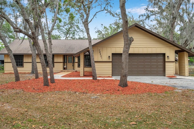 ranch-style house featuring a shingled roof, board and batten siding, a garage, and driveway