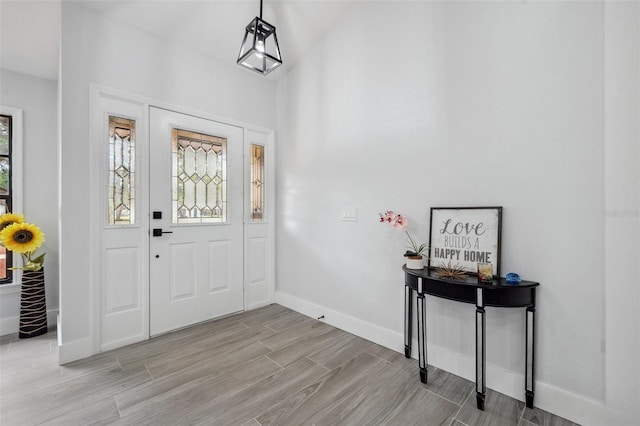 entryway featuring a high ceiling, baseboards, and wood finish floors