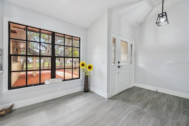 foyer entrance featuring baseboards and vaulted ceiling