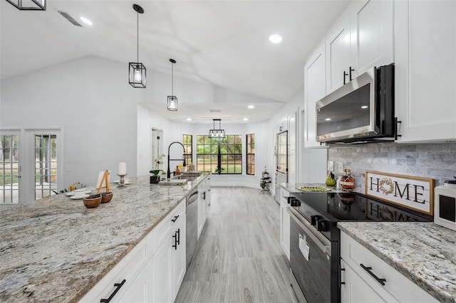 kitchen featuring light wood-style floors, vaulted ceiling, visible vents, appliances with stainless steel finishes, and a sink