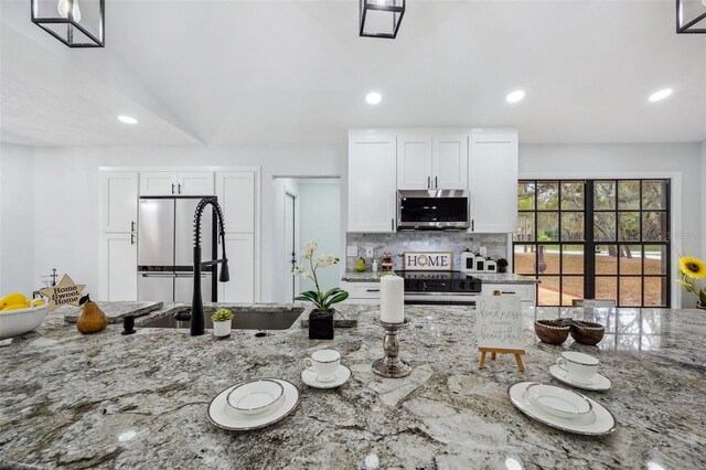 kitchen featuring stainless steel microwave, light stone counters, recessed lighting, backsplash, and range with electric stovetop