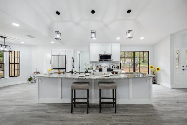 kitchen with white cabinets, recessed lighting, stainless steel appliances, light wood finished floors, and a spacious island