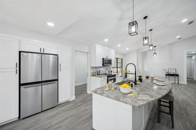 kitchen featuring stainless steel appliances, white cabinets, a sink, and light stone counters
