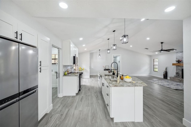 kitchen with baseboards, a ceiling fan, vaulted ceiling, and stainless steel appliances