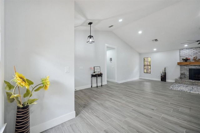 unfurnished living room with a fireplace, a ceiling fan, vaulted ceiling, visible vents, and baseboards