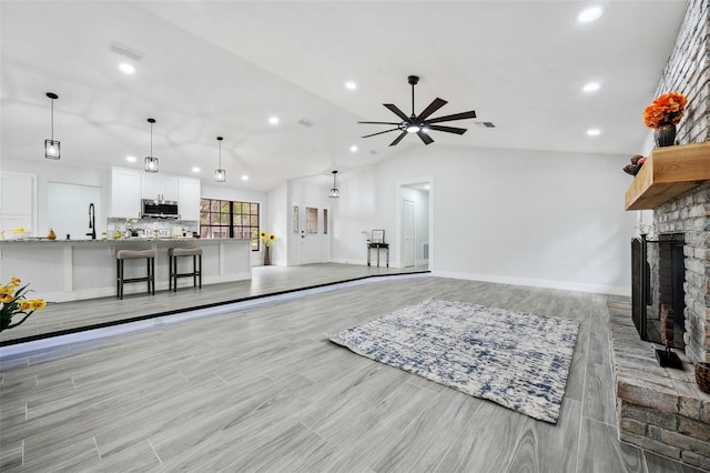 unfurnished living room featuring ceiling fan, a fireplace, lofted ceiling, and recessed lighting