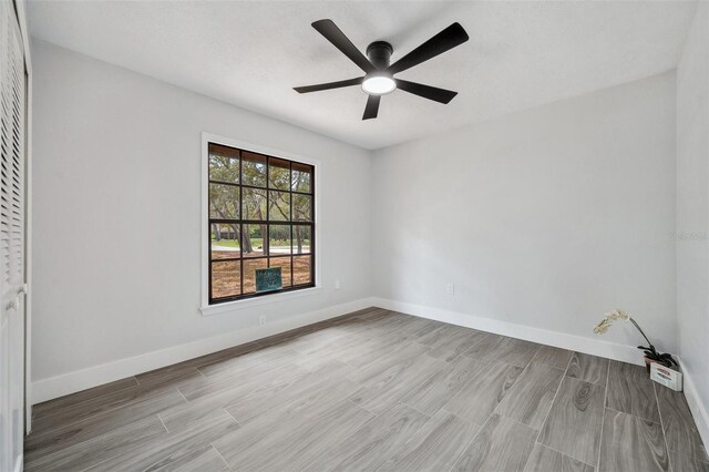 empty room with baseboards, a ceiling fan, and wood finished floors