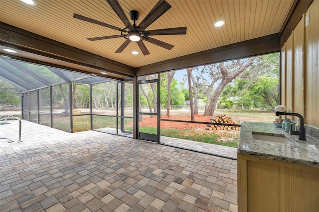 unfurnished sunroom featuring a sink and a ceiling fan