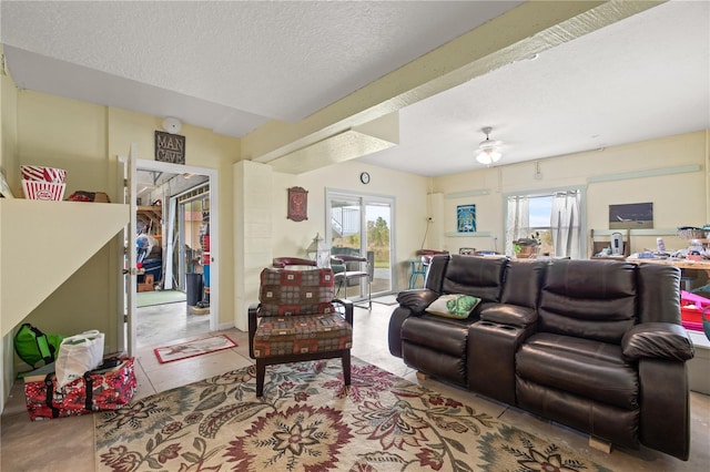 living area featuring a wealth of natural light, a textured ceiling, and a ceiling fan
