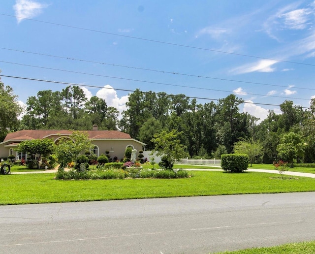 view of front facade featuring a front yard, a chimney, and stucco siding