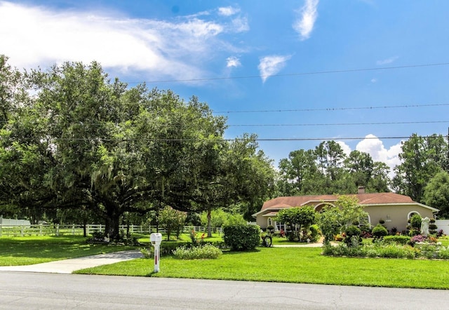 view of front of property featuring a front yard, driveway, fence, and a chimney