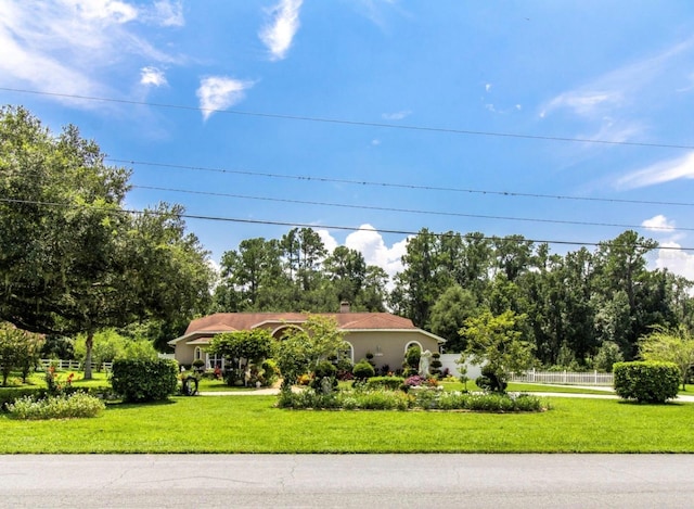 view of front of house featuring a chimney, a front yard, and fence