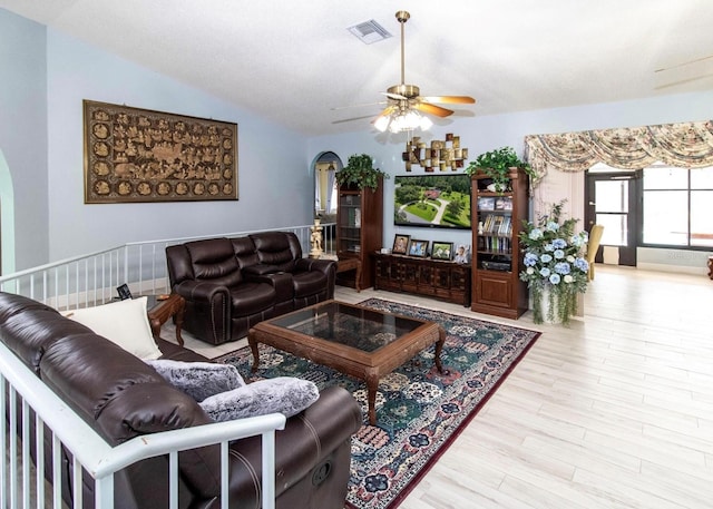 living room featuring visible vents, arched walkways, a ceiling fan, wood finished floors, and lofted ceiling