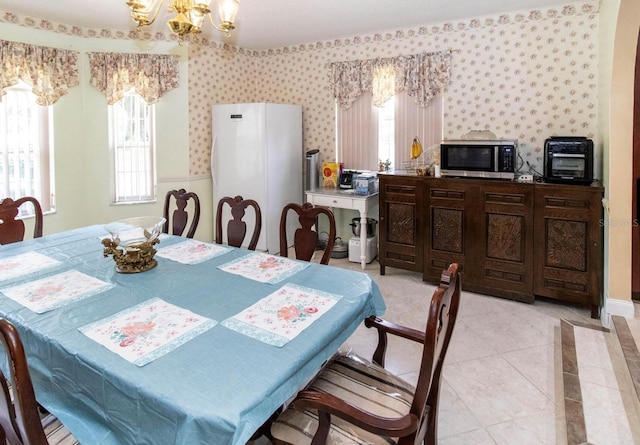 dining room featuring a chandelier, wallpapered walls, and light tile patterned flooring