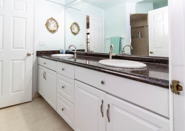 full bath featuring tile patterned flooring, double vanity, a sink, and a stall shower