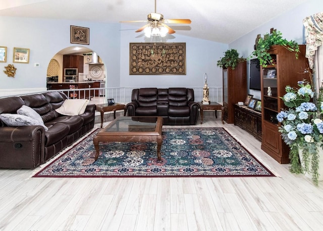 living area with ceiling fan, arched walkways, wood finished floors, and lofted ceiling