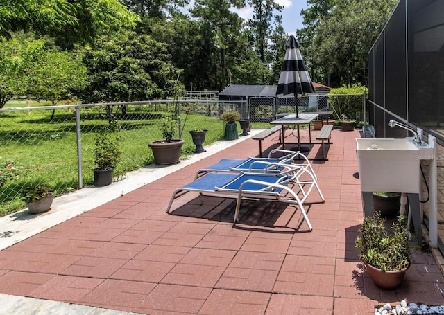 view of patio / terrace featuring a lanai, a sink, and fence