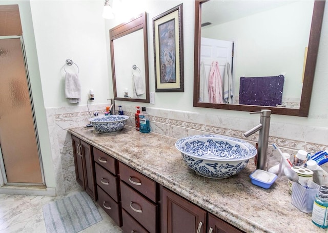 bathroom featuring a sink, tile walls, double vanity, and a stall shower