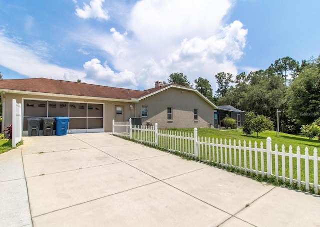 view of front of house featuring a front yard, an attached garage, concrete driveway, a fenced front yard, and stucco siding