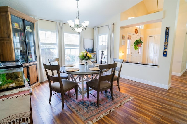 dining area featuring a chandelier, wood finished floors, baseboards, and lofted ceiling