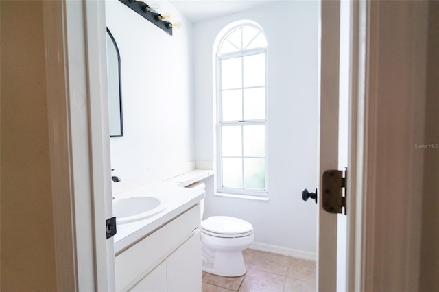 half bath featuring tile patterned floors, plenty of natural light, vanity, and toilet