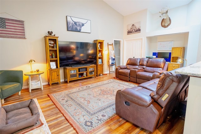 living room featuring high vaulted ceiling, baseboards, and wood finished floors